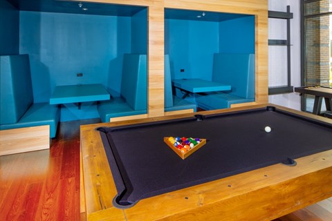 A pool table with a wooden frame and a black felt cloth is in the center of the room.