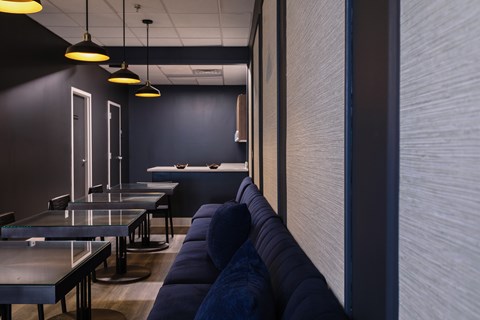 A modern dining area with dark walls and blue couches.