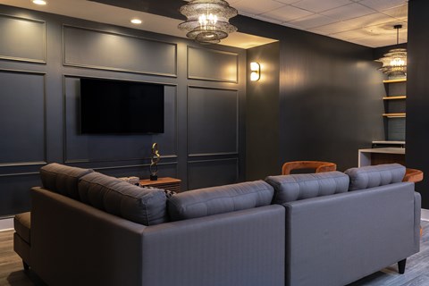 A modern living room with a grey sofa and a flat screen TV mounted on the wall.
