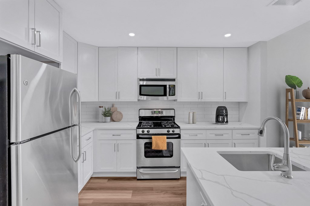 a white kitchen with stainless steel appliances and white cabinets