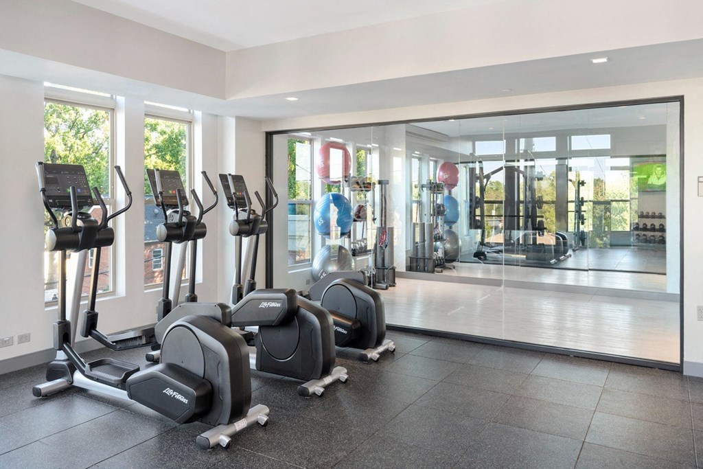 a gym with cardio equipment and a glass door