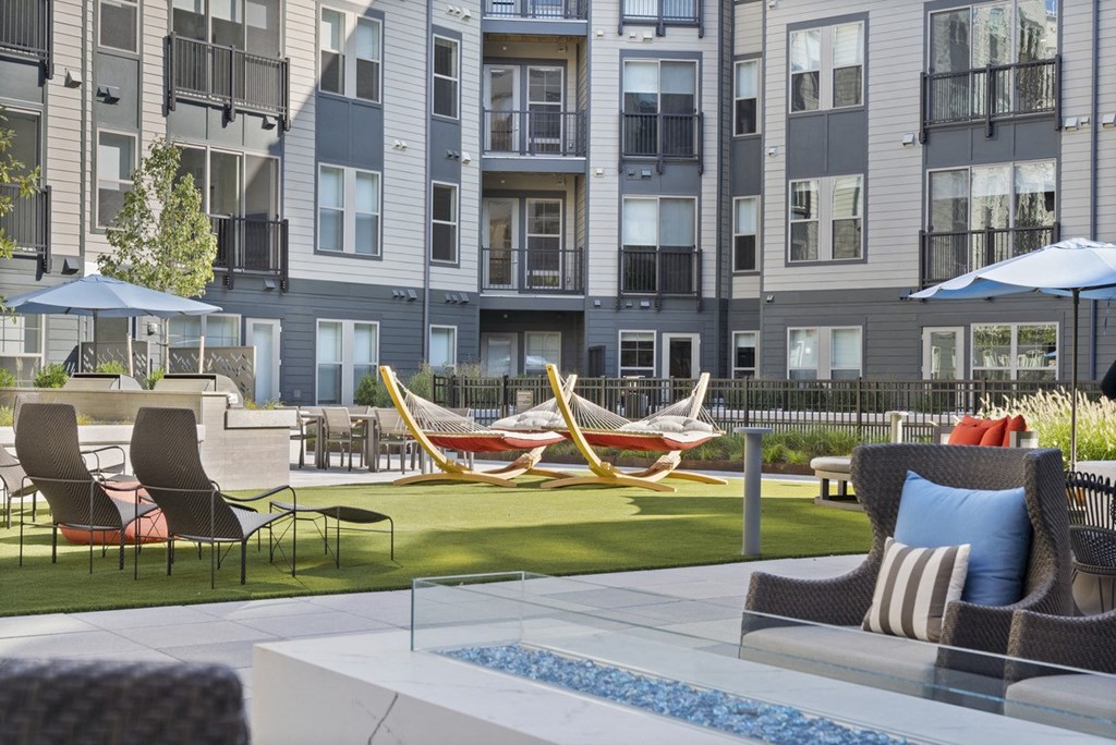 an outdoor lounge area with hammocks and chairs in front of an apartment building