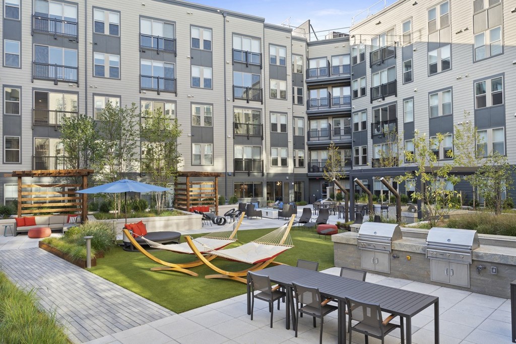 a rendering of an apartment courtyard with picnic tables and hammocks