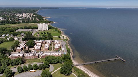 A large building sits on a grassy area next to a body of water.