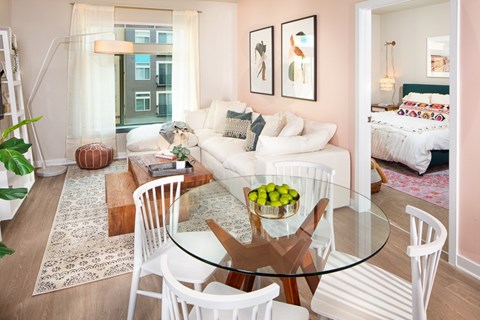 A modern living room with a glass table and white chairs.