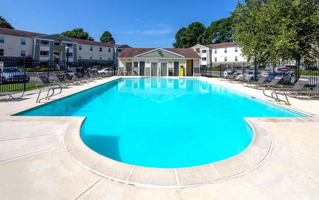 A large swimming pool with a blue tinted water surrounded by a concrete floor.