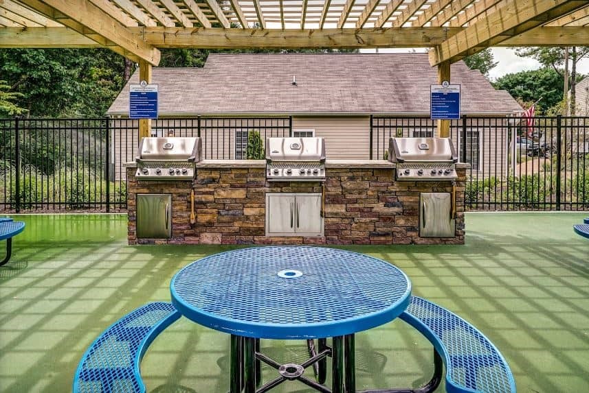 a patio with a table and chairs in front of a grill