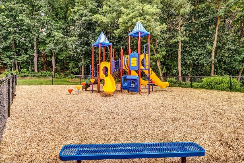 a playground with a blue bench and a yellow swing set