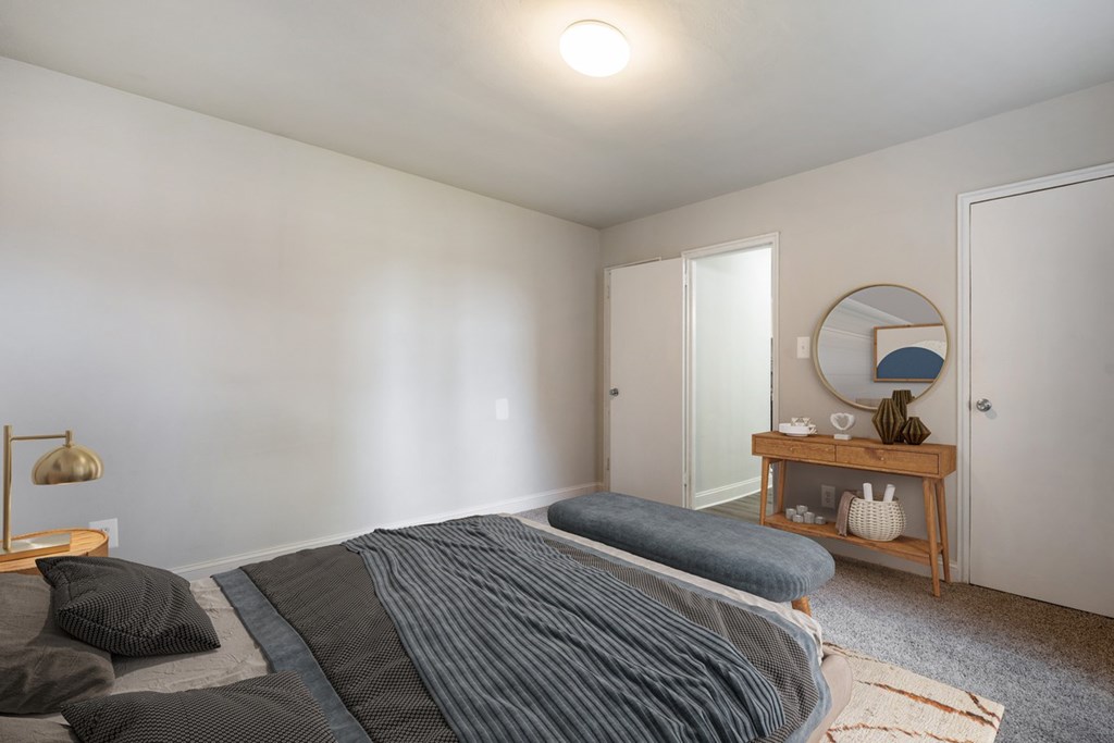 A bedroom with a bed, a nightstand, and a mirror.