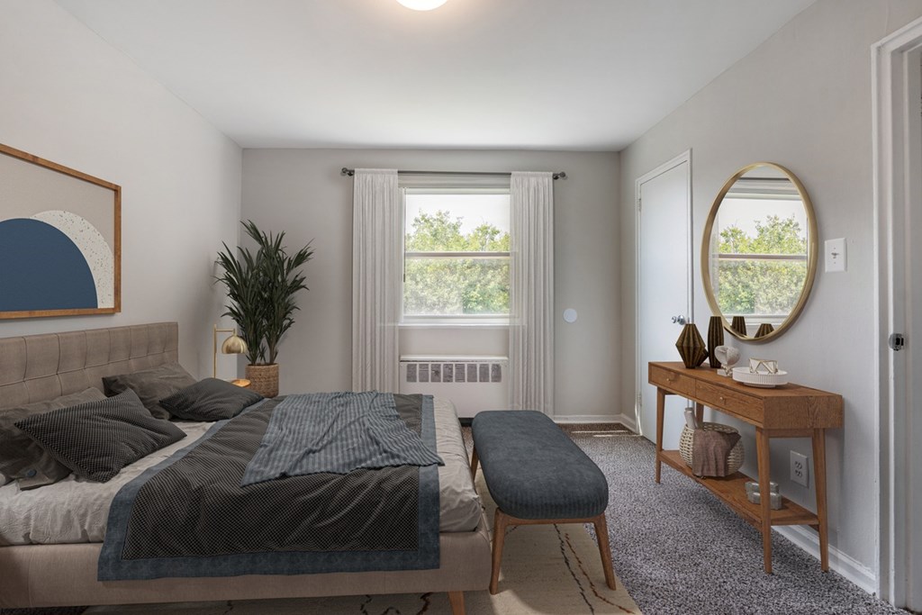 A bedroom with a bed, a bench, and a mirror.