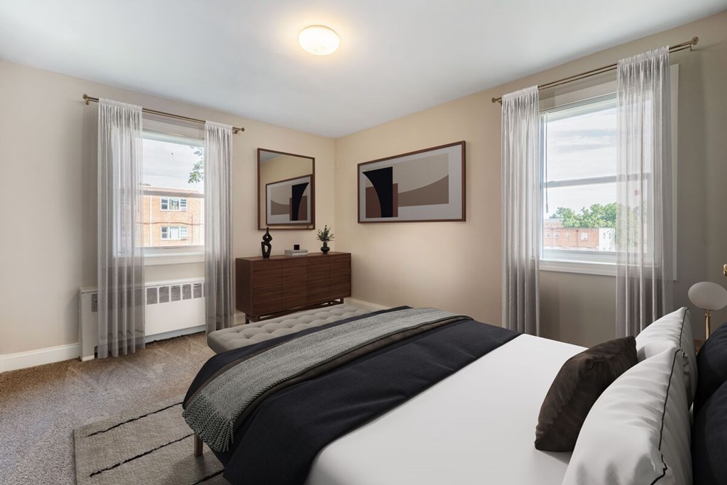 A bedroom with a large bed and a window with curtains.