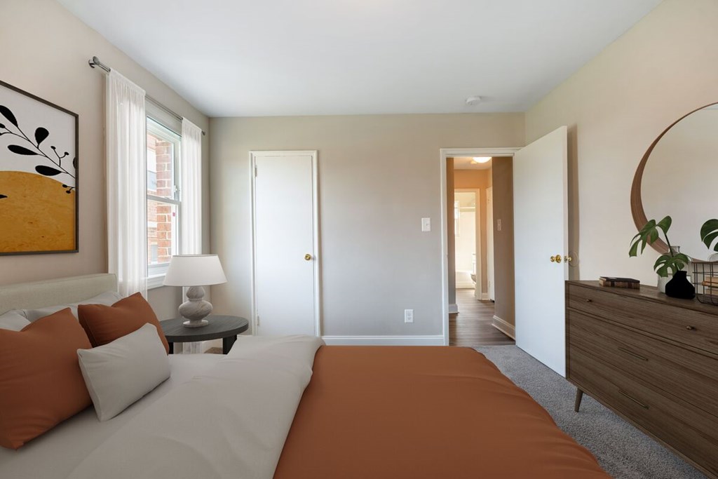 A bedroom with a bed, nightstand, lamp, and a painting on the wall.