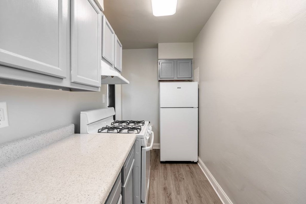 A kitchen with a white fridge, stove and cabinets.