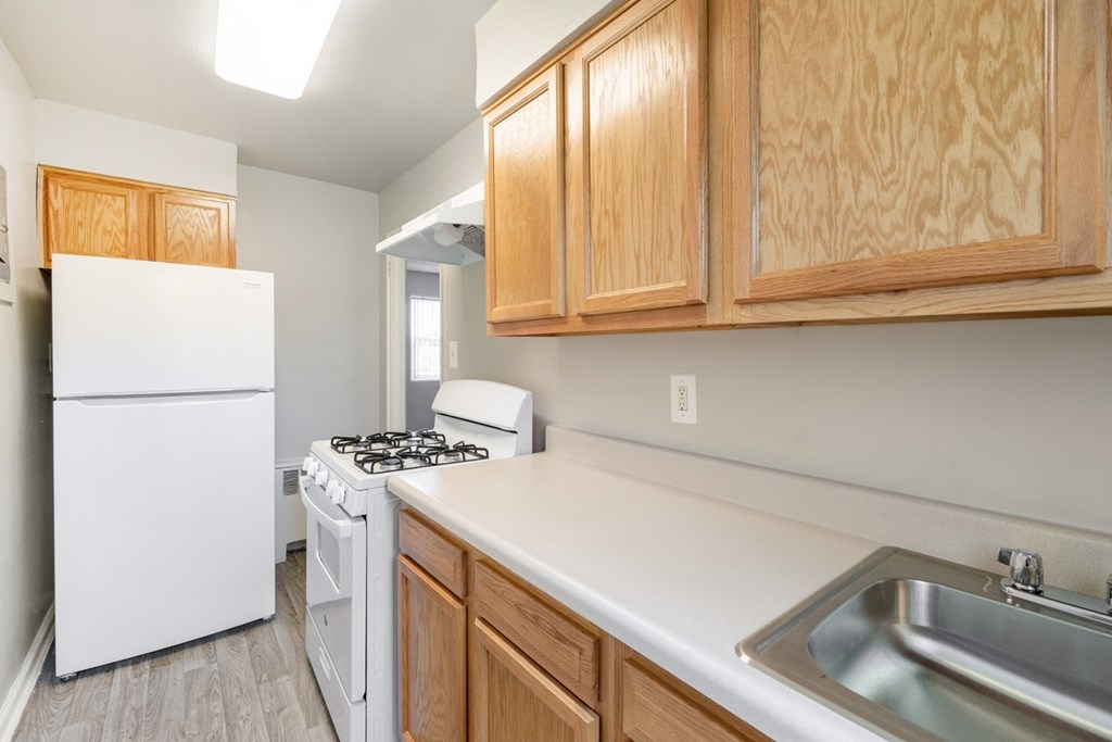 A kitchen with a white fridge, a white stove, and wooden cabinets.