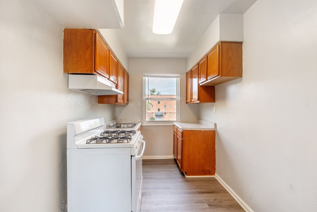 A kitchen with a white stove and wooden cabinets.