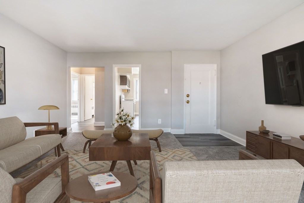 A living room with a couch, coffee table, and a flat screen TV mounted on the wall.