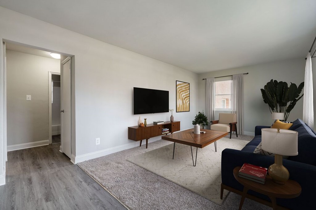 A living room with a blue couch, a wooden coffee table, and a flat-screen TV mounted on the wall.