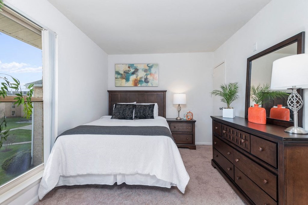 a bedroom with a bed and a dresser and a window