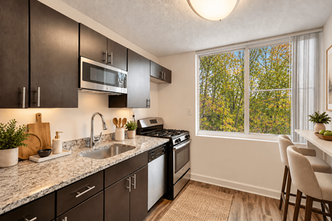 A kitchen with a sink, stove, and microwave.