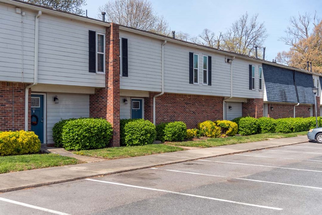 a brick and white building with a parking lot