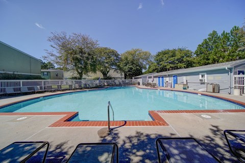 A large outdoor swimming pool with a diving board and sun loungers.