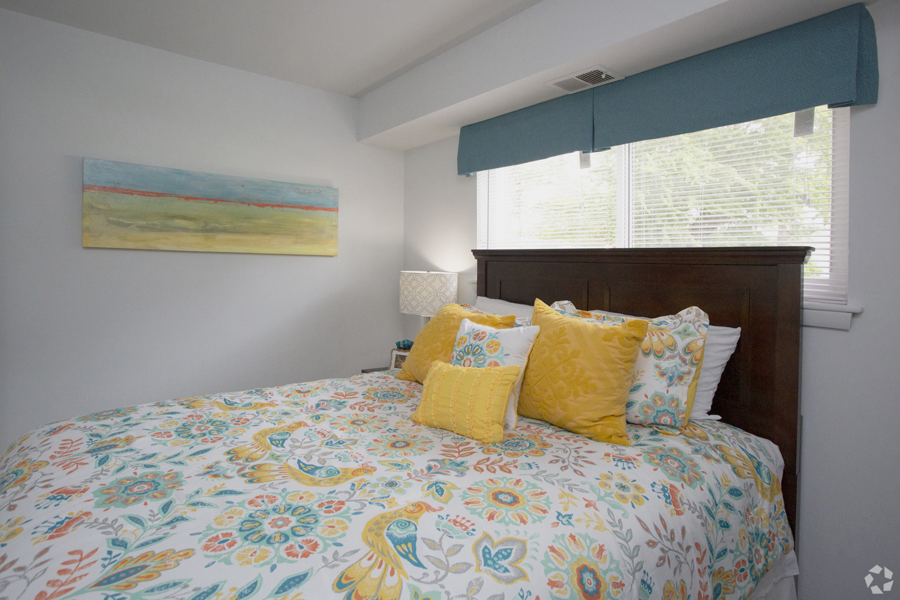 a bedroom with a large bed with a colorful comforter and pillows