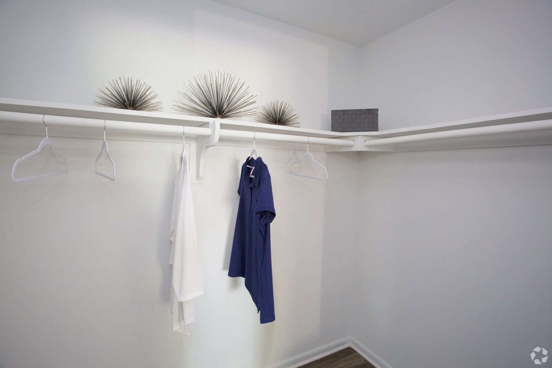 a white closet with white hangers and a blue shirt hanging from a white rail