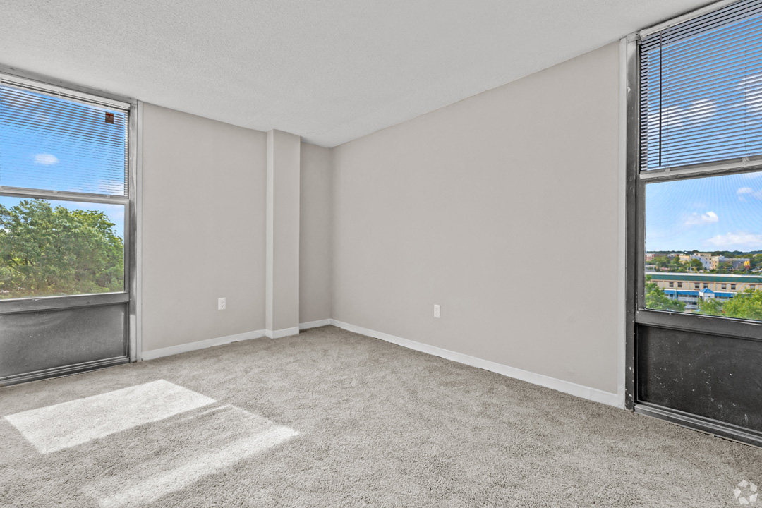 an empty room with large windows and a carpeted floor