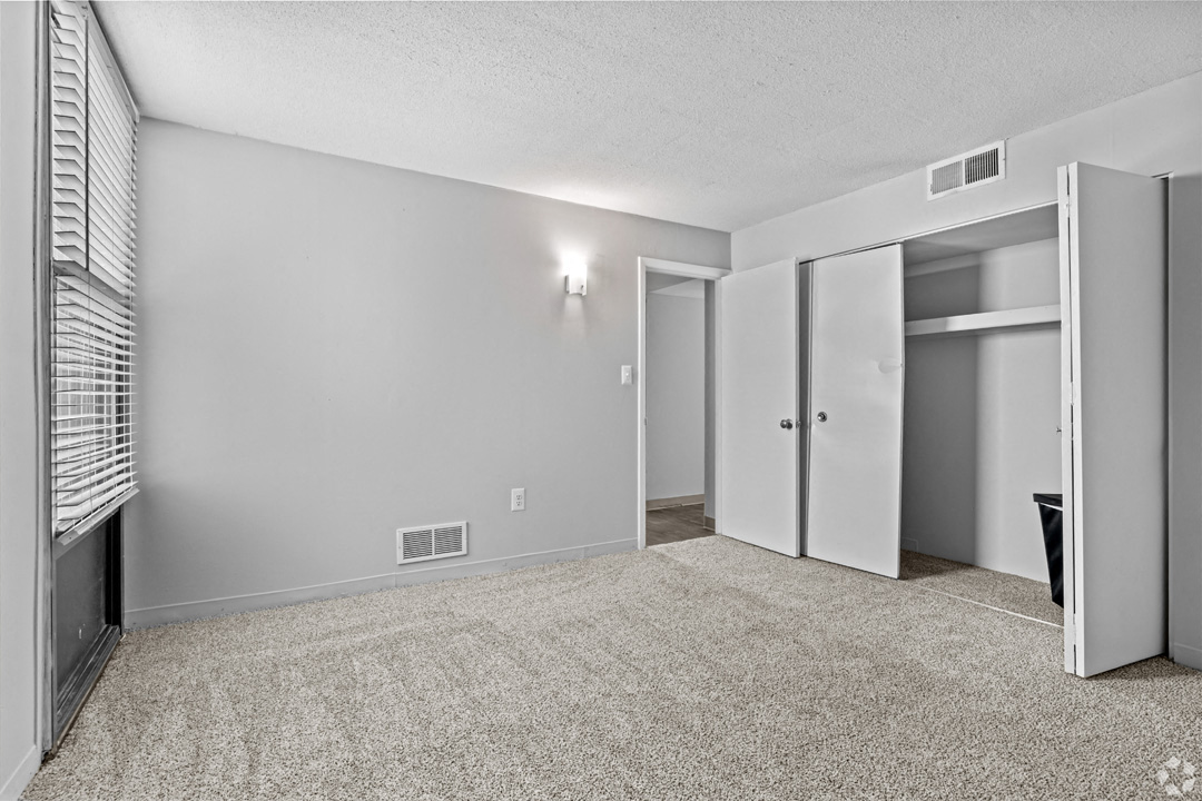 the living room is empty and has mirrored closet doors