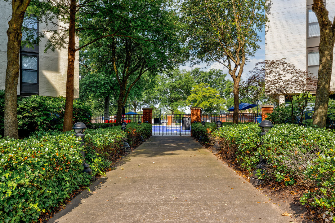 a sidewalk in front of a building with trees and bushes