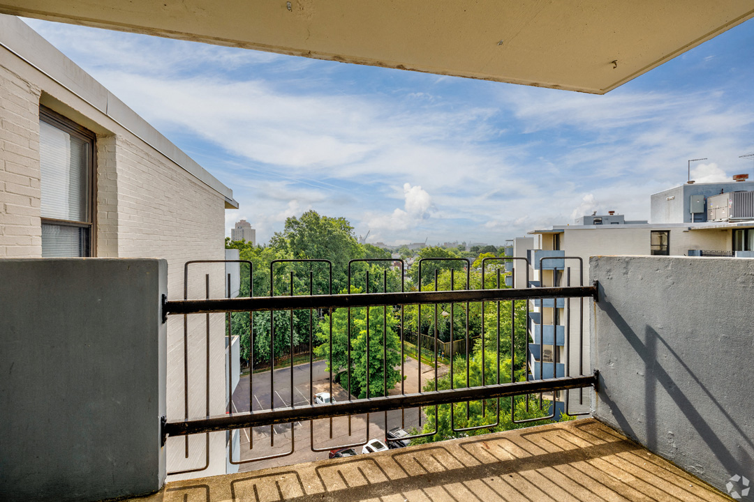 the balcony has a view of the trees and the city in the distance