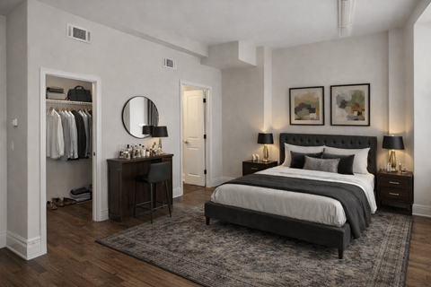 A bedroom with a large bed, a dressing area, and a rug on the floor.