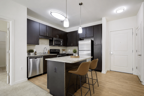 A kitchen with a white island and black cabinets.