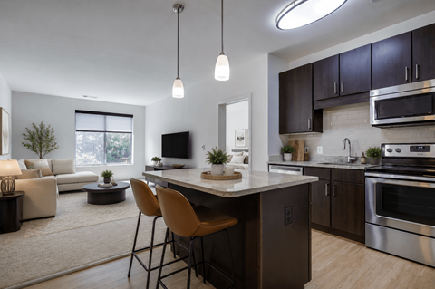 A modern kitchen with a large island and chairs.