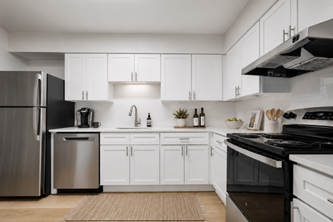 A modern kitchen with white cabinets and stainless steel appliances.