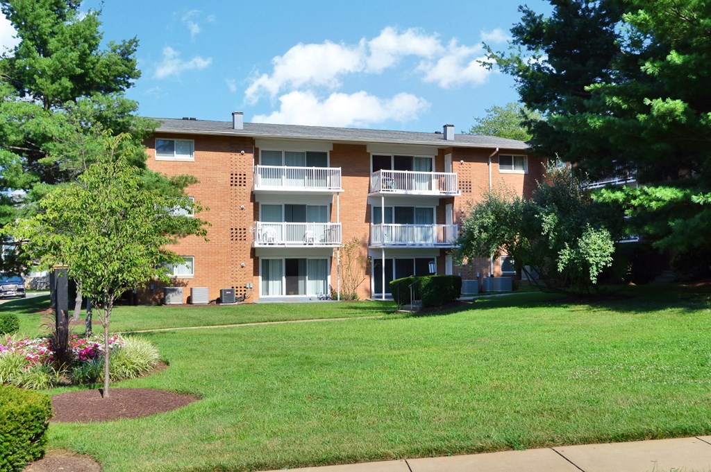 an apartment building with a lawn and trees in front of it