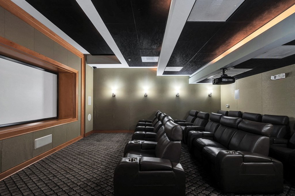 a large screening room with black leather seats and a projector screen