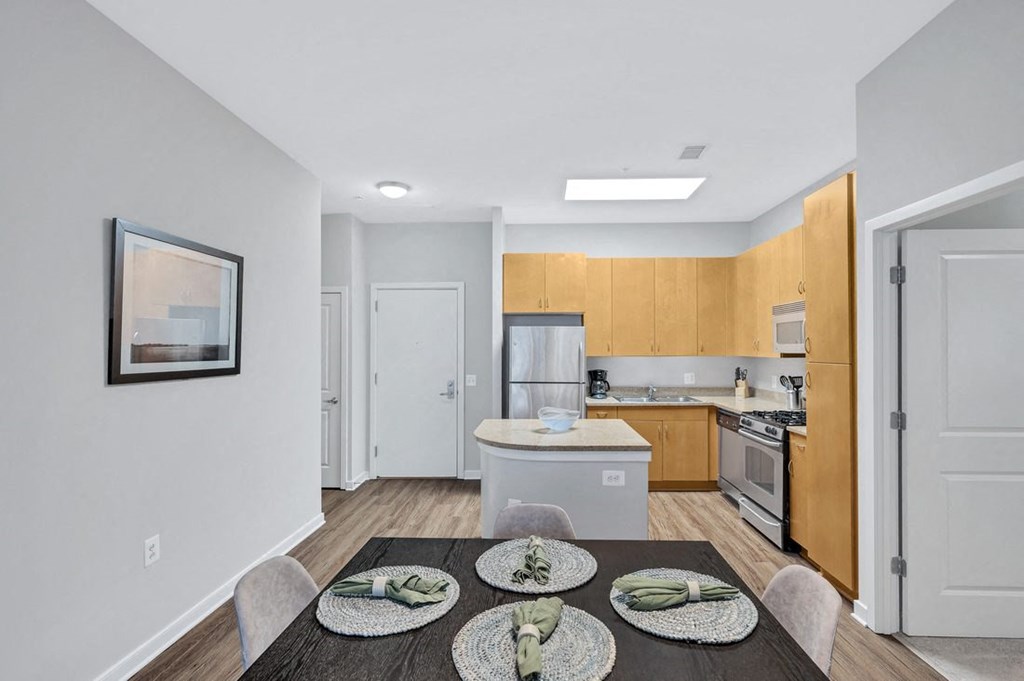 a dining area with a table and chairs and a kitchen in the background