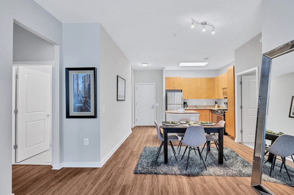 a dining room with a table and chairs and a kitchen in the background