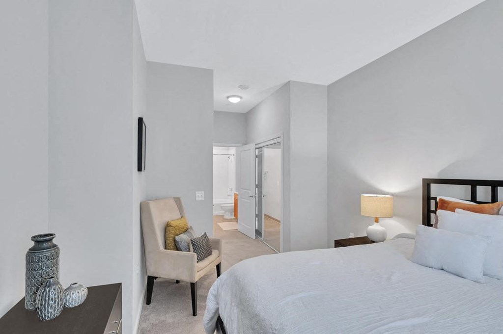 a bedroom with a bed and a chair in front of a mirror