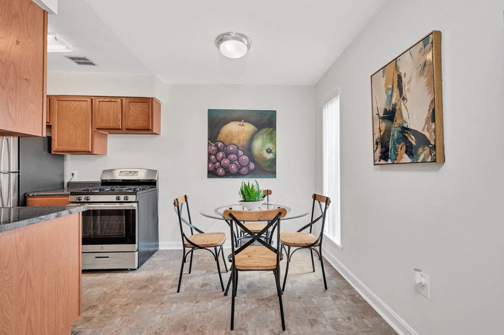 a dining area with a table and chairs and a kitchen in the background