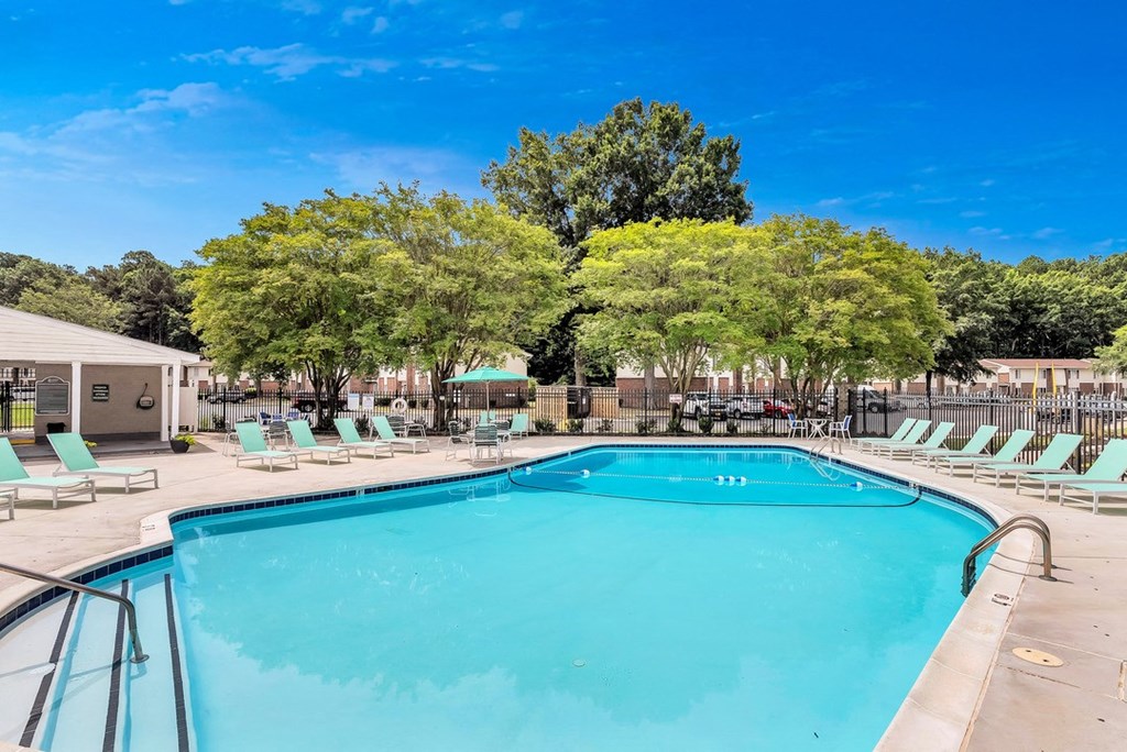 a swimming pool with chairs around it and trees in the background