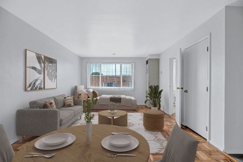 A dining room with a table set for two and a couch in the background.