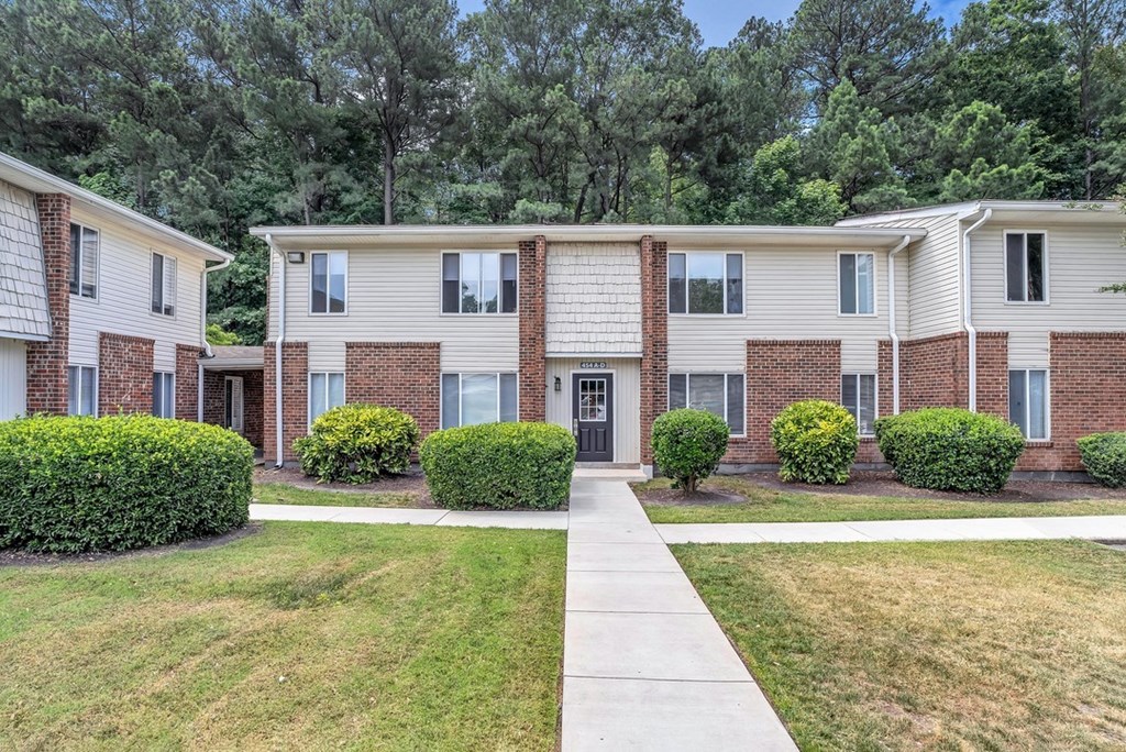 a white and brick apartment building with grass and bushes