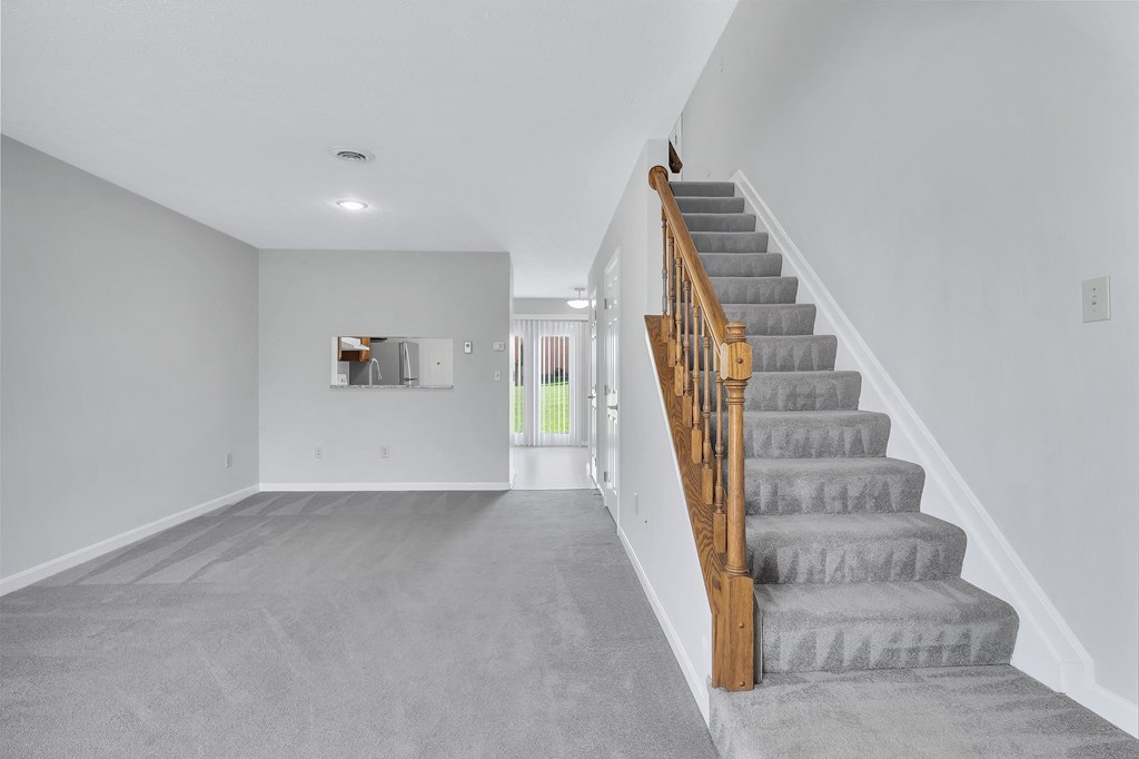 a gray carpeted stairway in a white house with stairs and a carpet floor