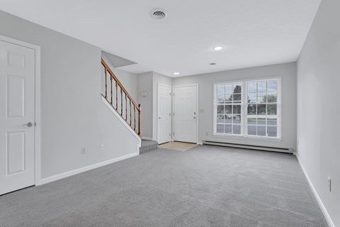 an empty living room with a staircase and a large window