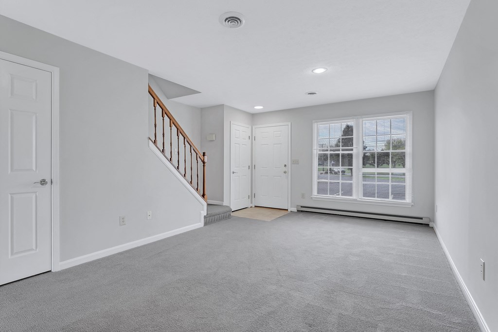 an empty living room with a staircase and a large window