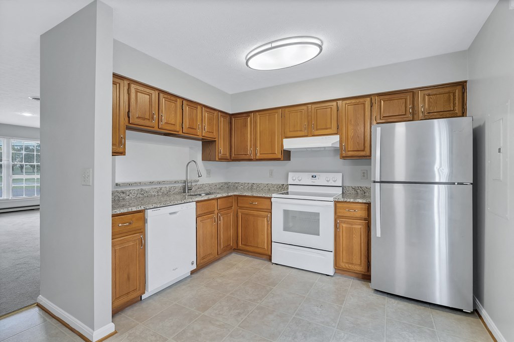 an empty kitchen with wooden cabinets and stainless steel appliances