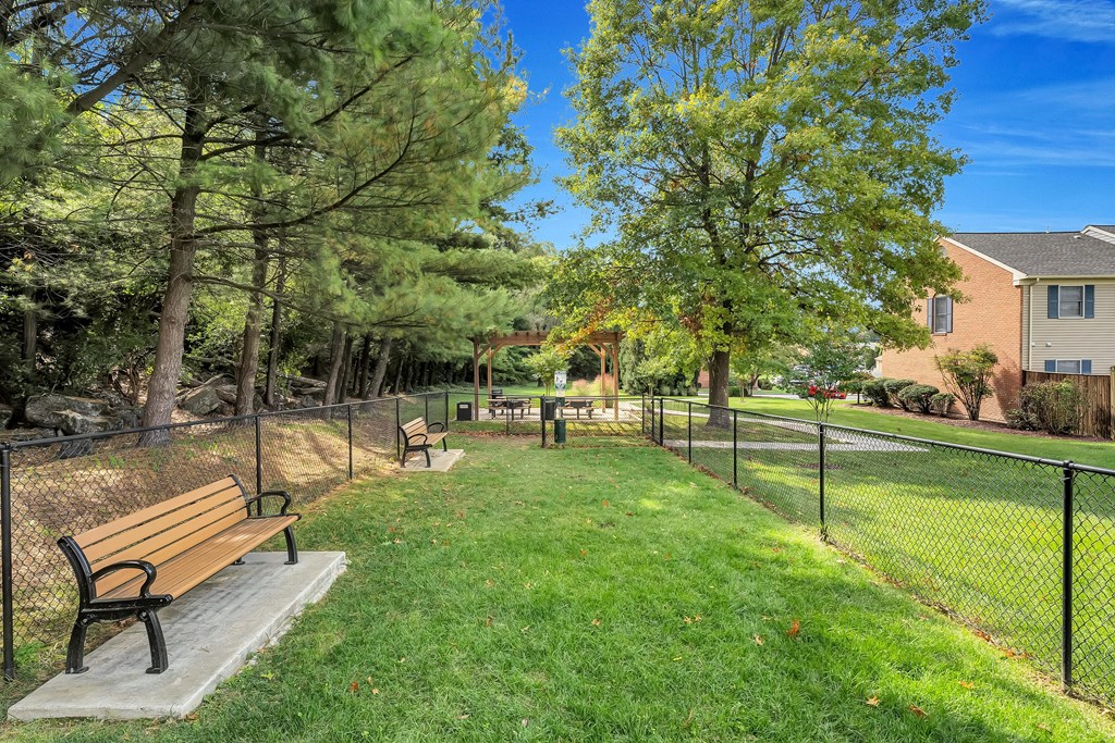 a park with benches next to a chain link fence