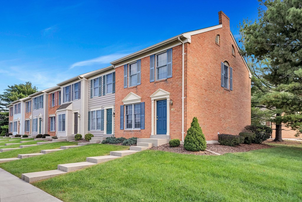 a brick building with blue doors and grass and trees
